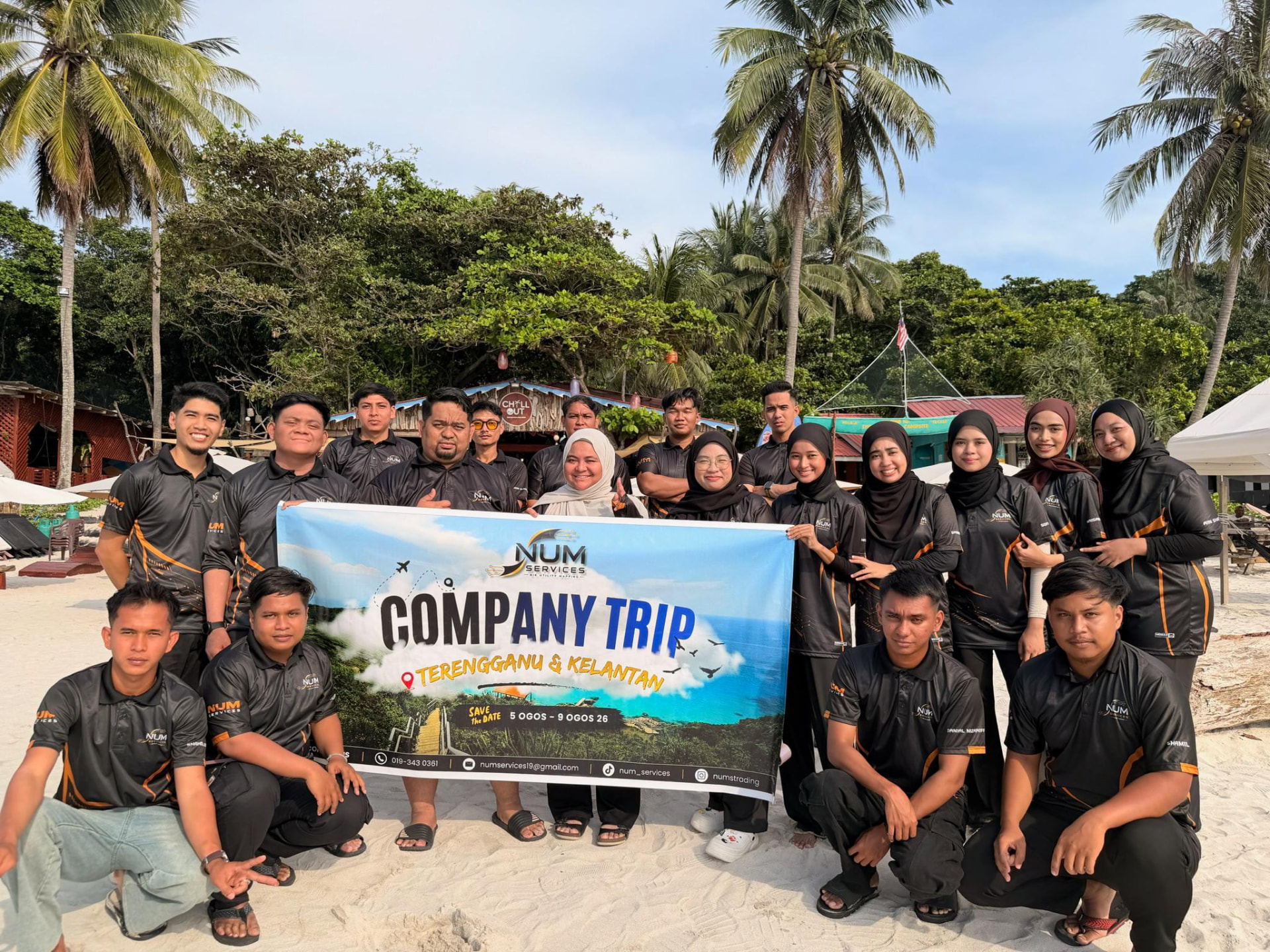 NUMS TRADING team holding a Company Trip Terengganu & Kelantan banner on a beach
