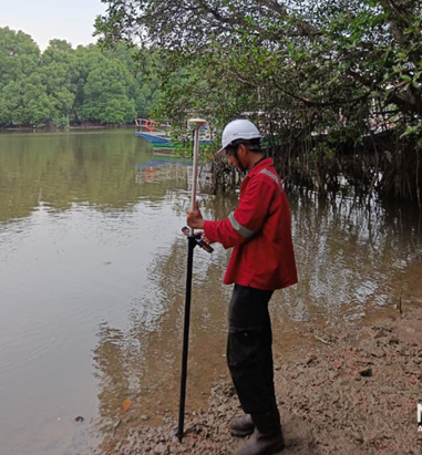 Surveyor recording GPS RTK points beside a mangrove riverbank