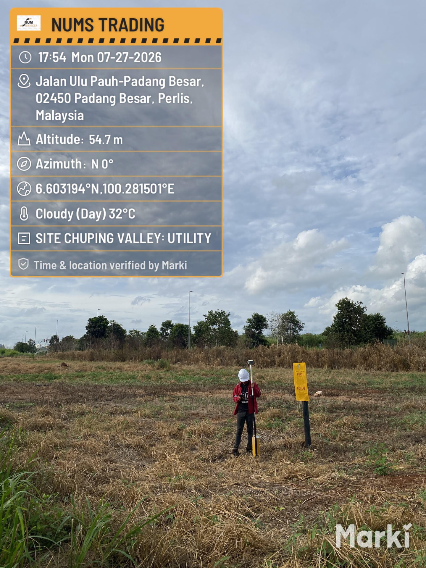 Surveyor with GPS RTK pole beside a pipeline warning marker at Chuping Valley, Perlis